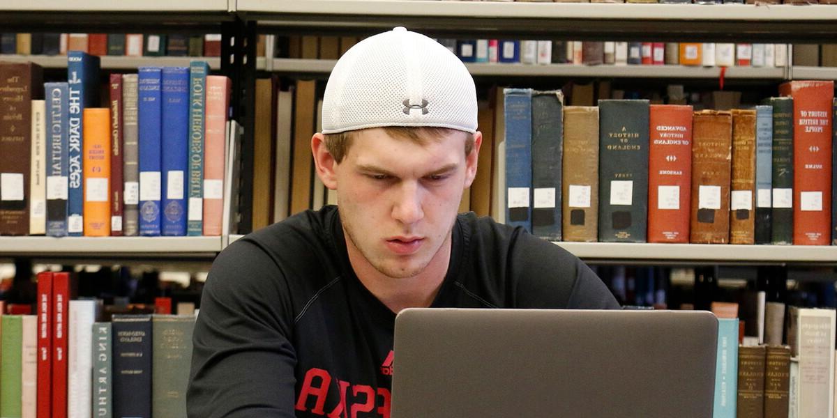 一个男生在图书馆用笔记本电脑